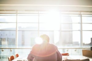 Back of man sitting at desk with sun glare