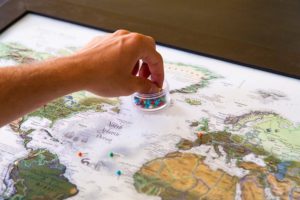 a hand picking up a pin on a world map